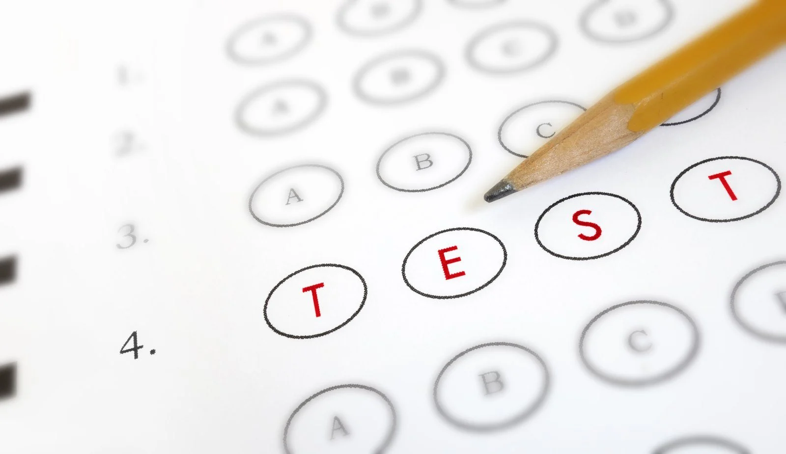 A pencil on a bubble answer sheet spelling TEST